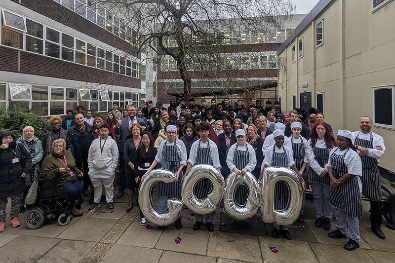 students in the courtyard with silver balloons spelling out GOOD